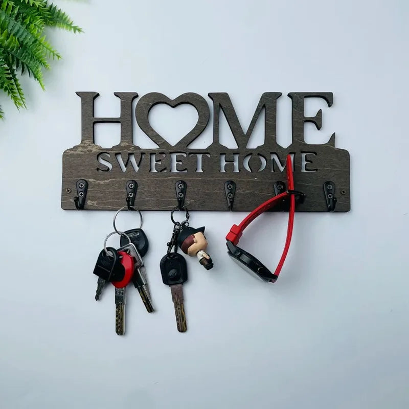 Wooden key holder with 'HOME SWEET HOME' text on a white wall.